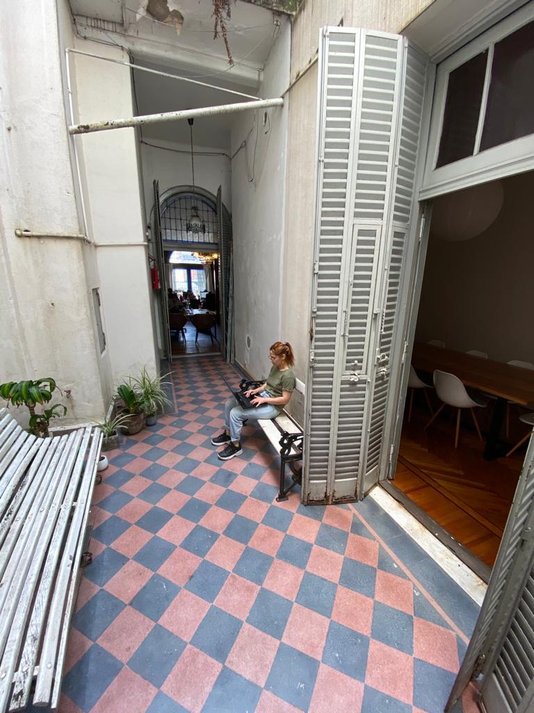 Patio interno con mosaicos rosa y gris originales, banco de madera y plantas — espacio común de Pawer Belgrano