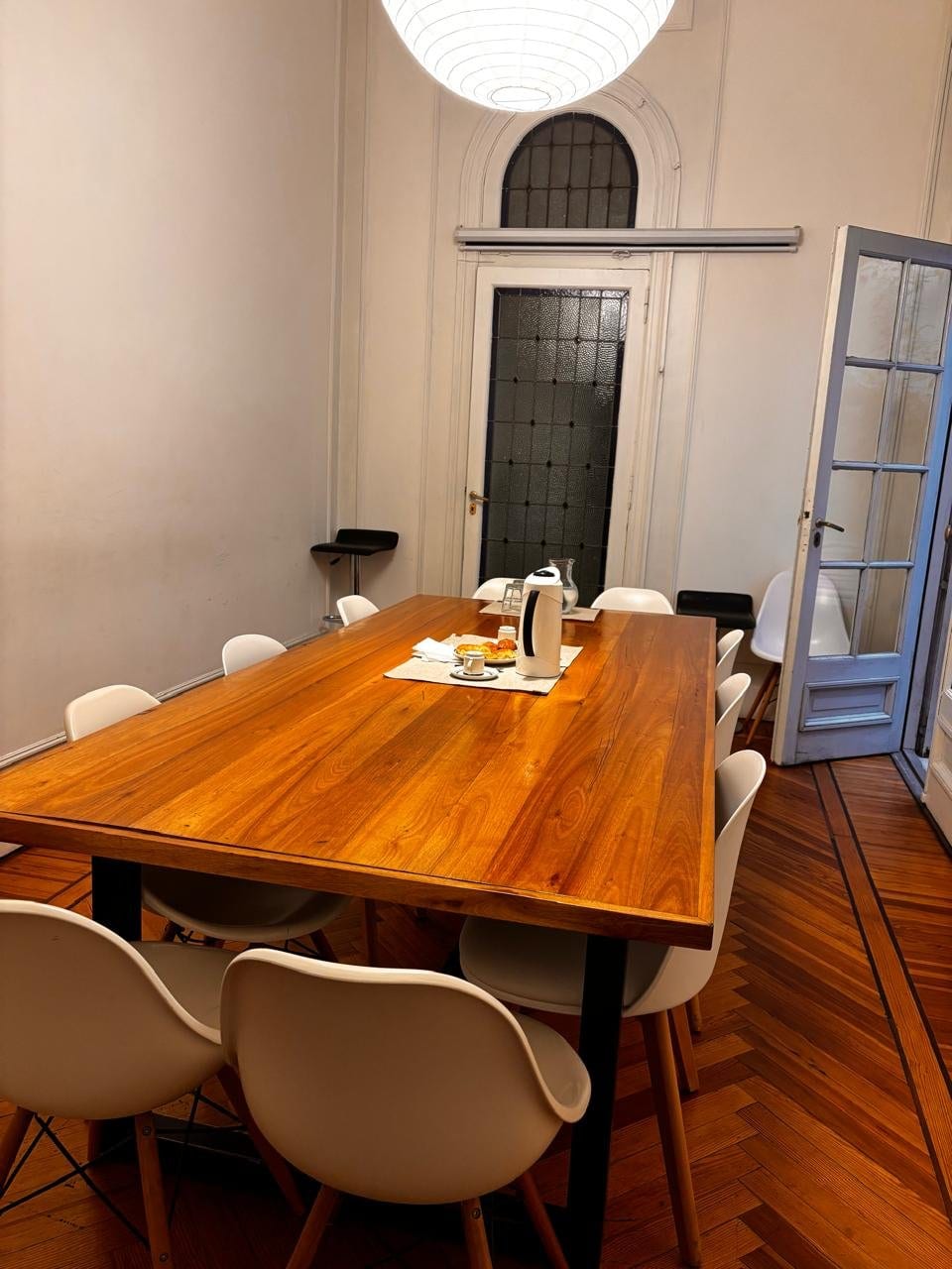 Sala de reuniones de Pawer Belgrano con mesa para 8 personas, sillas Eames blancas y lámpara de papel