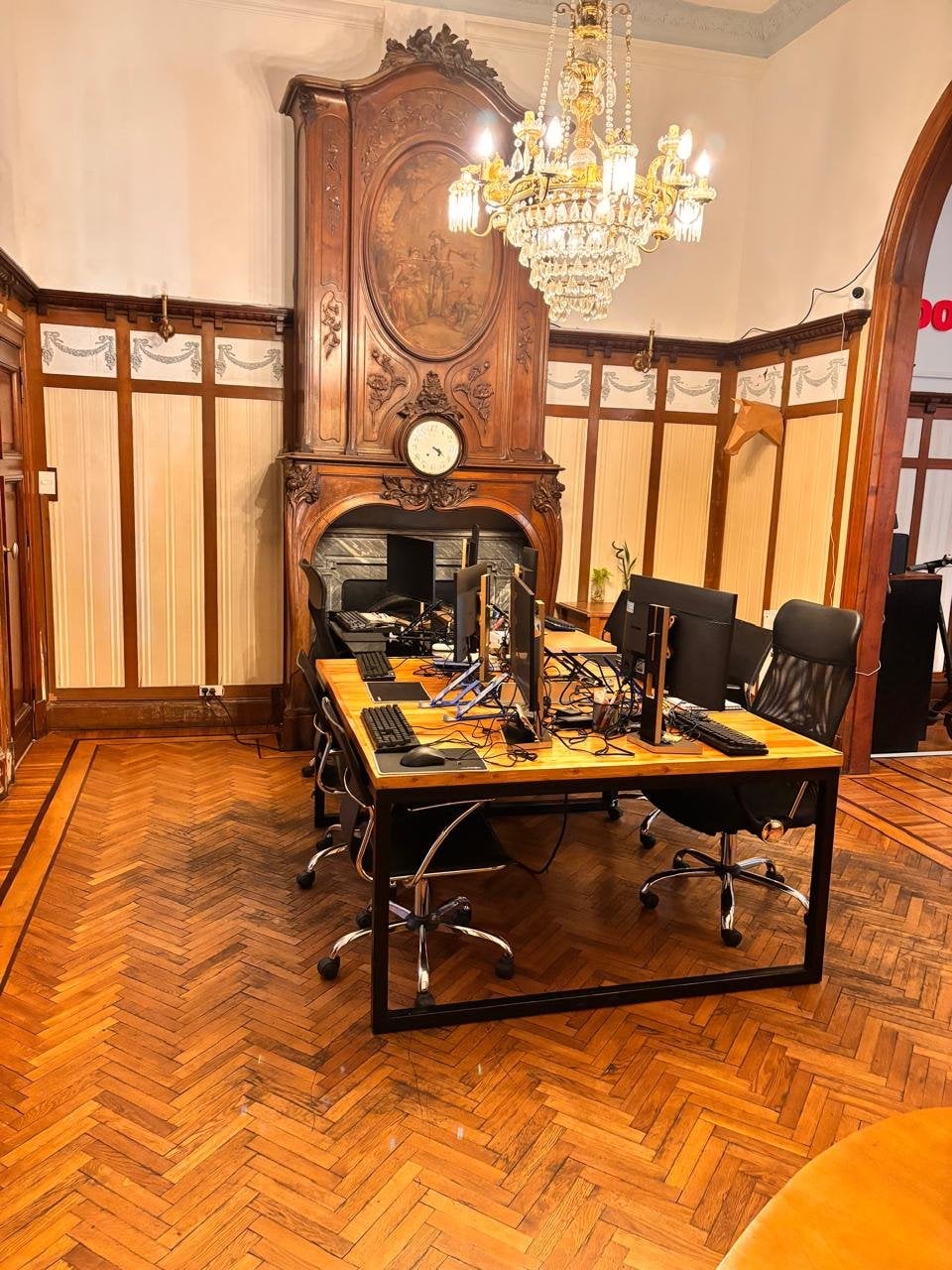 Sala con chimenea de mármol original, araña de cristal de bronce, parquet espina de pez y boiserie tallada en Pawer Belgrano — la pieza más arquitectónica de la casa